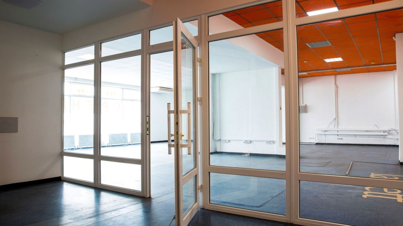 Empty office floor with glass partition doors and bare walls, ready for an office interior fit-out