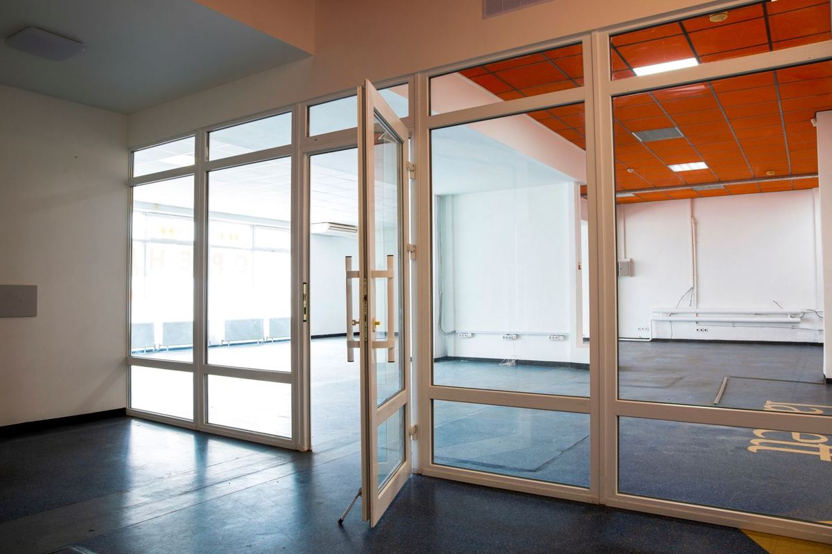 Empty office floor with glass partition doors and bare walls, ready for an office interior fit-out
